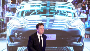 Tesla Inc CEO Elon Musk walks next to a screen showing an image of Tesla Model 3 car during an opening ceremony for Tesla China-made Model Y program in Shanghai