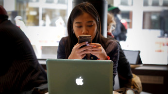 A woman uses her Apple iPhone and laptop in a cafe in lower Manhattan in New York City