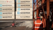 Worker is seen next to Maersk shipping containers at a logistics center near Tianjin por