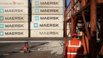Worker is seen next to Maersk shipping containers at a logistics center near Tianjin por