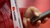 An attendee wears a badge strip with the logo of Huawei and a sign for 5G at the World 5G Exhibition in Beijing