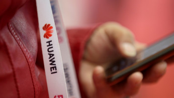 An attendee wears a badge strip with the logo of Huawei and a sign for 5G at the World 5G Exhibition in Beijing