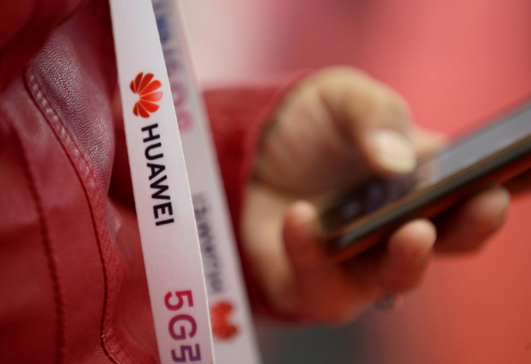 An attendee wears a badge strip with the logo of Huawei and a sign for 5G at the World 5G Exhibition in Beijing
