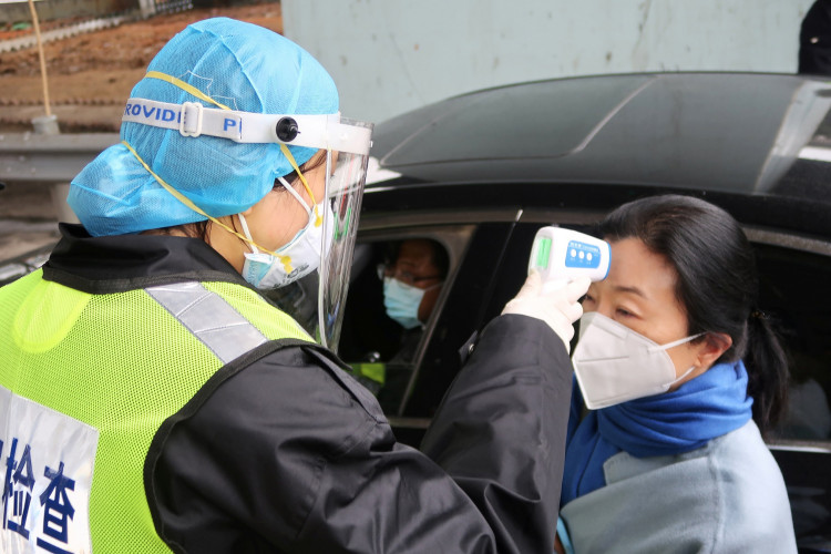 A security officer in a protective mask checks the temperature of a passenger following the outbreak of a new coronavirus, at an expressway toll station on the eve of the Chinese Lunar New Year celebrations
