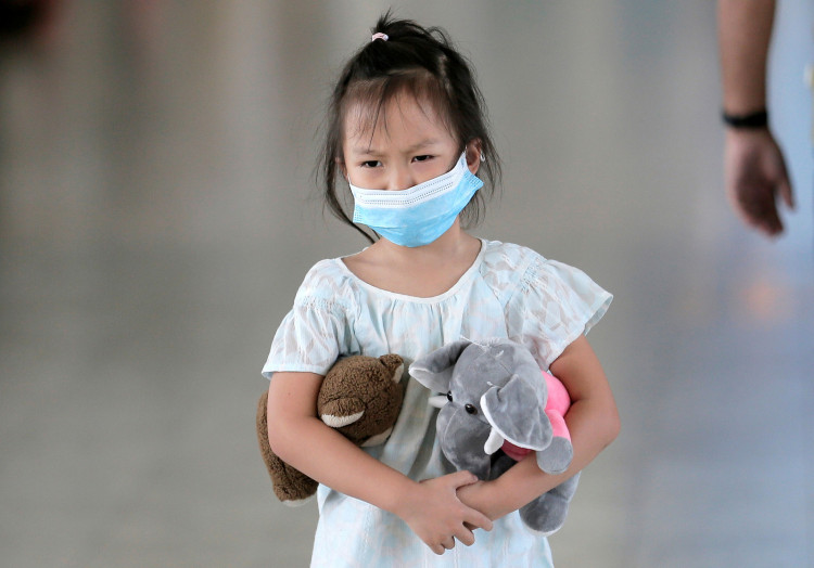 A girl wears a mask as she walks past a scanning machine monitoring people's temperature following the new coronavirus outbreak from China, at Bandaranaike international airport in Katunayake