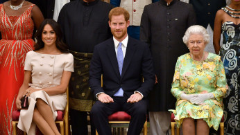 FILE PHOTO: Britain's Queen Elizabeth, Prince Harry and Meghan, the Duchess of Sussex pose for a picture with some of Queen's Young Leaders at a Buckingham Palace reception following the final Queen's Young Leaders Awards Ceremony, in London