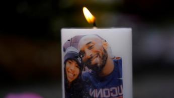 NBA basketball star Kobe Bryant and his daughter Gianna's image are shown on a burning candle as fans pay their respects at a memorial outside the Staples Center at L.A. Live in Los Angeles