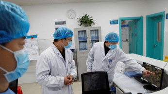 Doctors look at a screen that shows the ward where patients who are infected with the coronavirus are treated at the First People's Hospital in Yueyang