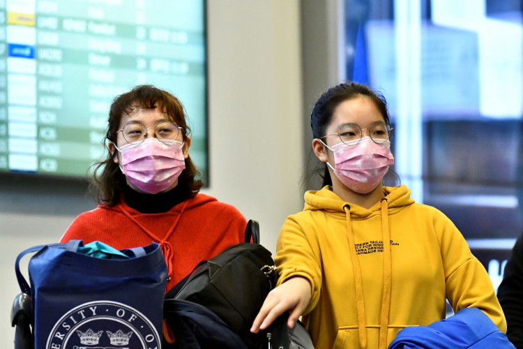 Travellers wearing masks arrive on a direct flight from China at Vancouver International Airport