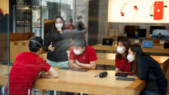 People wear face masks as they listen to a presentation in an Apple Store in the Sanlitun shopping district in Beijing as China is hit by an outbreak of the new coronavirus