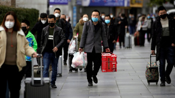 Passengers wearing masks walk outside the Shanghai railway station in Shanghai, China, as the country is hit by an outbreak of a new coronavirus