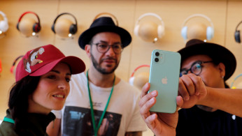 People look at an app on the new iPhone inside the new Apple Store in Mexico City