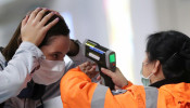 A worker checks the temperature of a passenger arriving into Hong Kong International Airport with an infrared thermometer, following the coronavirus outbreak in Hong Kong, China, February 7, 2020. 