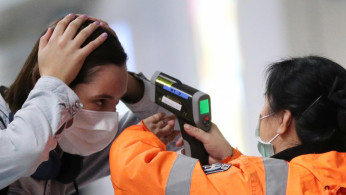 A worker checks the temperature of a passenger arriving into Hong Kong International Airport with an infrared thermometer, following the coronavirus outbreak in Hong Kong, China, February 7, 2020. 