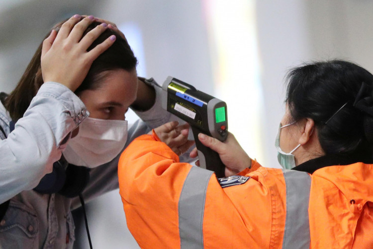 A worker checks the temperature of a passenger arriving into Hong Kong International Airport with an infrared thermometer, following the coronavirus outbreak in Hong Kong, China, February 7, 2020. 