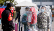 Passengers wearing masks and covered with plastic bags walk outside the Shanghai railway station in Shanghai