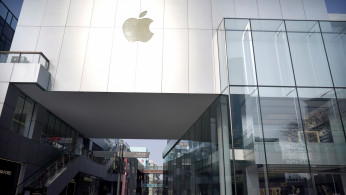Man wearing a face mask walks past a closed Apple store at Sanlitun in Beijing