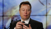 SpaceX founder and chief engineer Elon Musk looks at his mobile phone during a post-launch news conference 