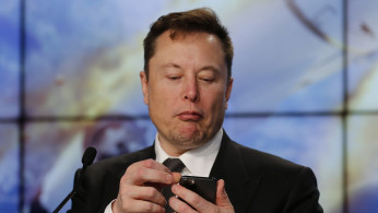 SpaceX founder and chief engineer Elon Musk looks at his mobile phone during a post-launch news conference 
