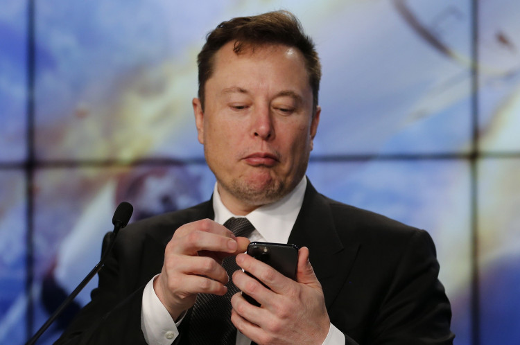 SpaceX founder and chief engineer Elon Musk looks at his mobile phone during a post-launch news conference 