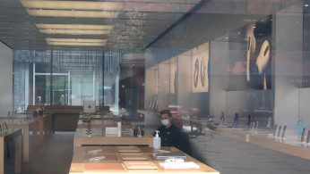 Security personnel wearing a face mask is seen in a closed Apple store at Sanlitun in Beijing