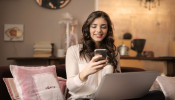 A woman sitting on the sofa while looking at her phone.