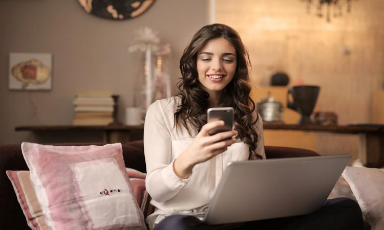 A woman sitting on the sofa while looking at her phone.