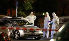 Forensic experts work around a damaged car after a shooting in Hanau near Frankfurt