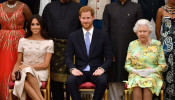 FILE PHOTO: Britain's Queen Elizabeth, Prince Harry and Meghan, the Duchess of Sussex pose for a picture with some of Queen's Young Leaders at a Buckingham Palace reception following the final Queen's Young Leaders Awards Ceremony, in London