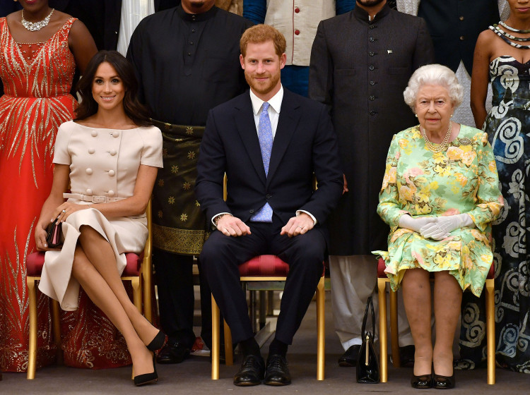 FILE PHOTO: Britain's Queen Elizabeth, Prince Harry and Meghan, the Duchess of Sussex pose for a picture with some of Queen's Young Leaders at a Buckingham Palace reception following the final Queen's Young Leaders Awards Ceremony, in London