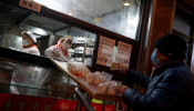 A sales woman slides buns down a slope at a non-contact food stall in Beijing as the country is hit by an outbreak of the novel coronavirus, China