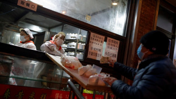 A sales woman slides buns down a slope at a non-contact food stall in Beijing as the country is hit by an outbreak of the novel coronavirus, China