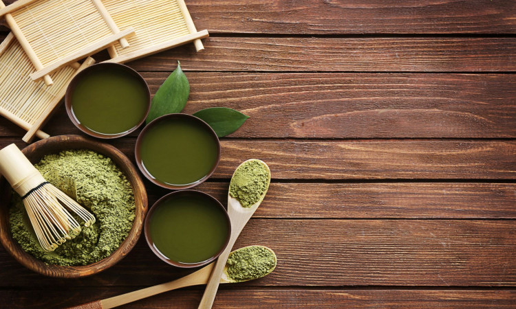 Bowl of green powder on a brown wooden surface.