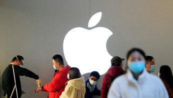 People wearing protective masks wait for checking their temperature in an Apple Store in Shanghai
