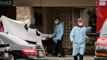 Medics transfer a patient on a stretcher to an ambulance at the Life Care Center of Kirkland, the long-term care facility linked to the two of three confirmed coronavirus cases in the state, in Kirkland