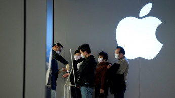 People wearing protective masks wait for checking their temperature in an Apple Store, in Shanghai