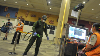 A medical officer sprays disinfectant on an entrance gate at the international terminal of I Gusti Ngurah Rai airport.