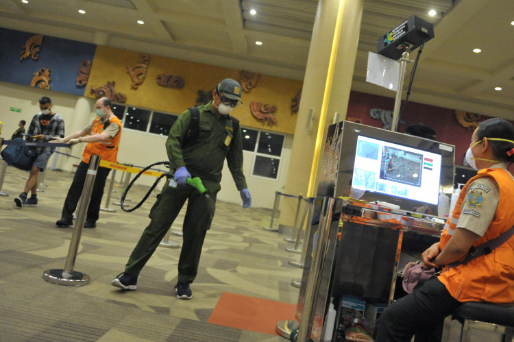A medical officer sprays disinfectant on an entrance gate at the international terminal of I Gusti Ngurah Rai airport.