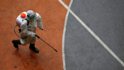 A volunteer from Indonesia's Red Cross, wearing a protective suit, walks while carrying a disinfectant sprayer at a school closed amid the spread of coronavirus (COVID-19) in Jakarta