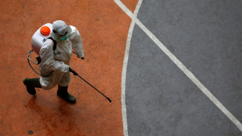 A volunteer from Indonesia's Red Cross, wearing a protective suit, walks while carrying a disinfectant sprayer at a school closed amid the spread of coronavirus (COVID-19) in Jakarta