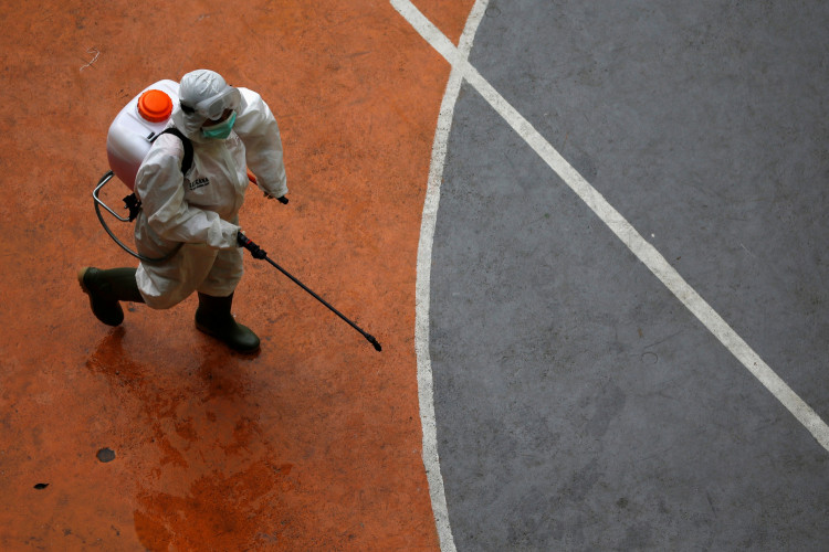 A volunteer from Indonesia's Red Cross, wearing a protective suit, walks while carrying a disinfectant sprayer at a school closed amid the spread of coronavirus (COVID-19) in Jakarta