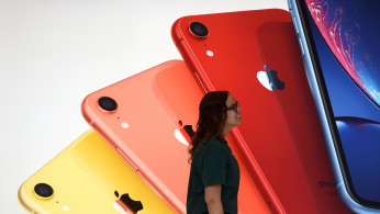 An Apple Store employee walks past an illustration of iPhones at the new Apple Carnegie Library during the grand opening and media preview in Washington