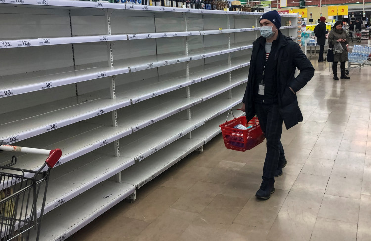 A man, wearing a protective mask, walks past empty shelves in a store, due to the fear of coronavirus disease (COVID-19) outbreak, in Moscow