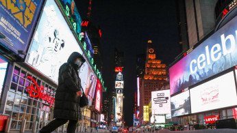 A person in a face mask walks through an almost empty Times Square as the coronavirus disease (COVID-19) outbreak continued in Manhattan, New York City