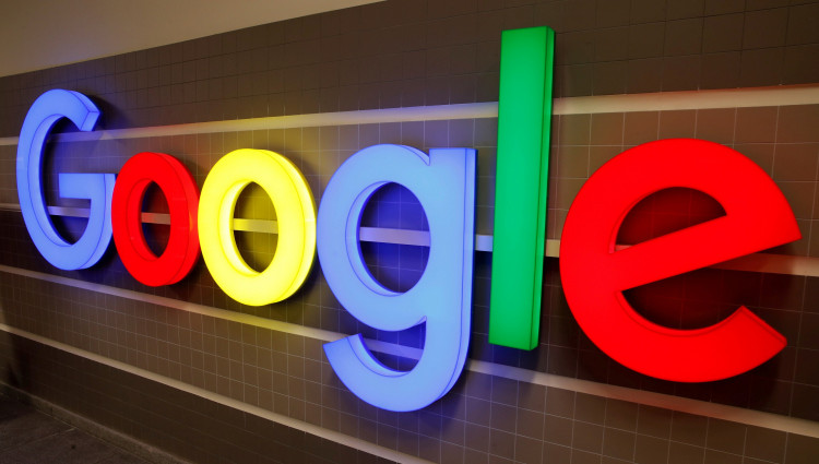 An illuminated Google logo is seen inside an office building