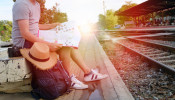 Man sitting behind black backpack along railway.