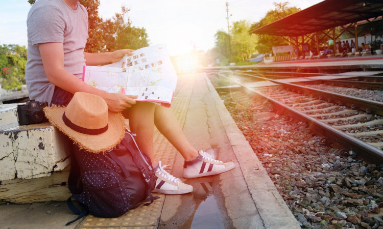 Man sitting behind black backpack along railway.