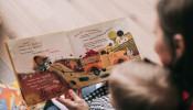 Woman reading book to toddler.