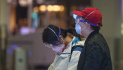 Passengers wear protective masks and gloves as they wait for their check-in for an Air China flight at the airport in Frankfurt, Germany
