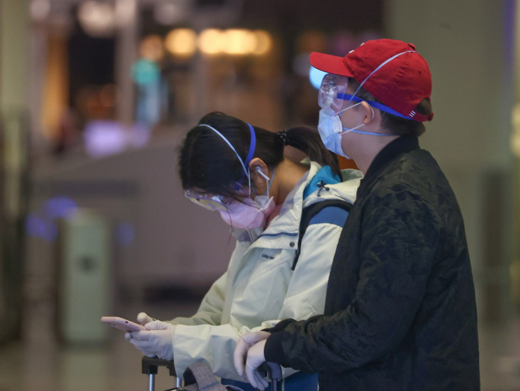 Passengers wear protective masks and gloves as they wait for their check-in for an Air China flight at the airport in Frankfurt, Germany
